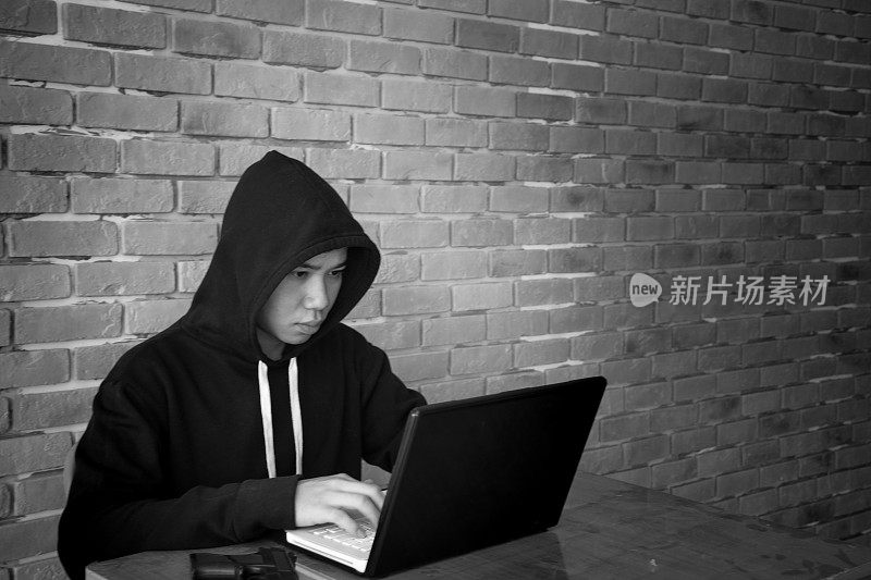 一名黑客盗窃笔记本电脑/网络安全概念数据的黑白照片